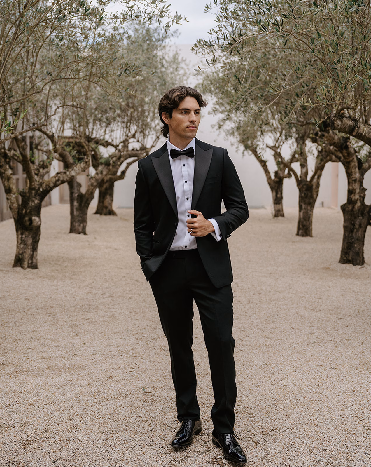 Man in tuxedo among olive trees, Black Jacket Suiting Brisbane.